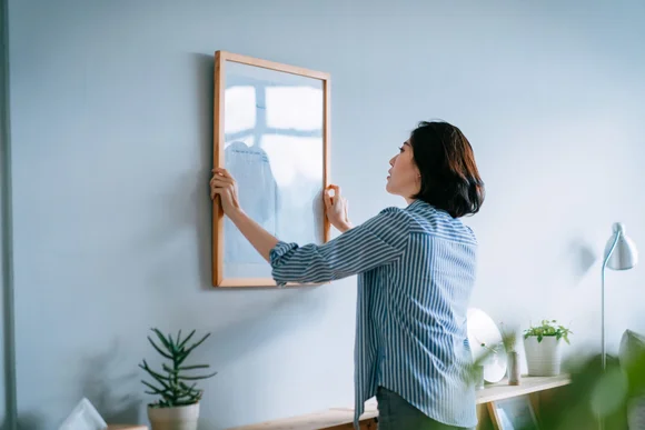 Person bringt Bild an Wand an